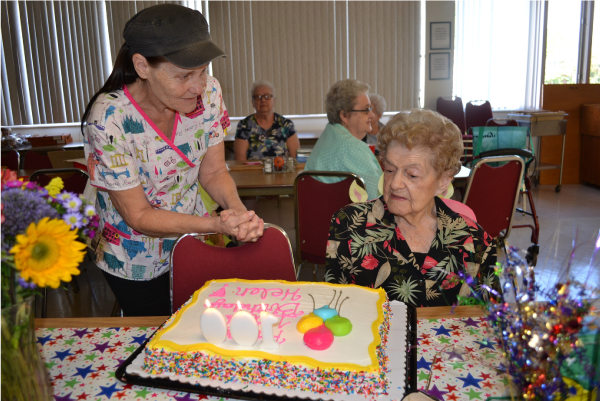 Picture of a cake being presented to a woman at the Senior Center