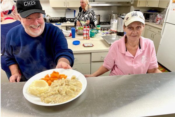 Picture of a man and woman presenting a plate of food at the Senior Center