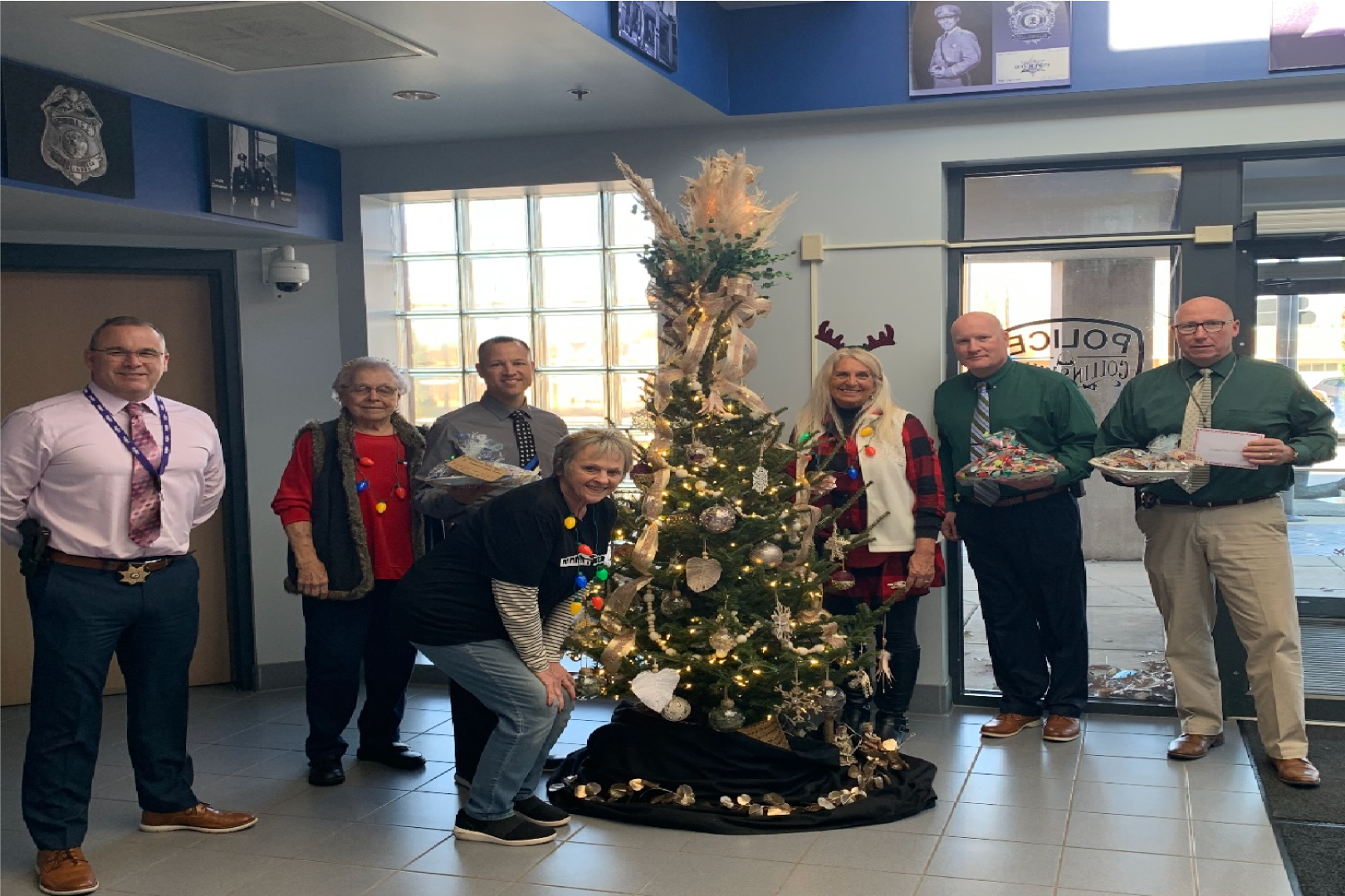 Picture of a group of men and womne standing around a Christmas tree at the Senior Center